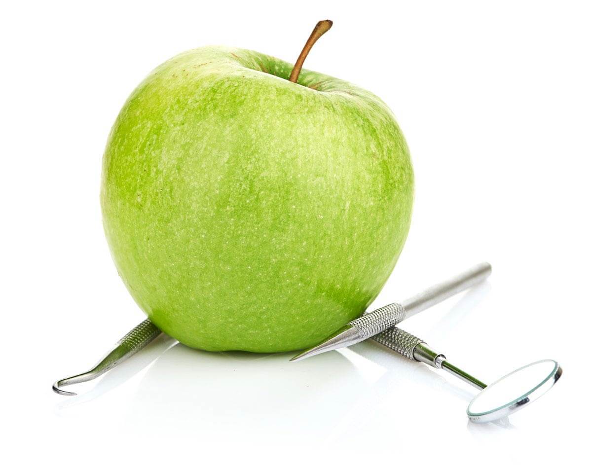 Яблоко и стоматологические инструменты