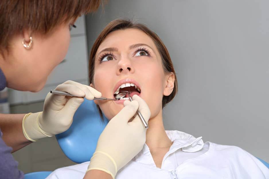 Стоматолог осматривает ротовую полость пациента